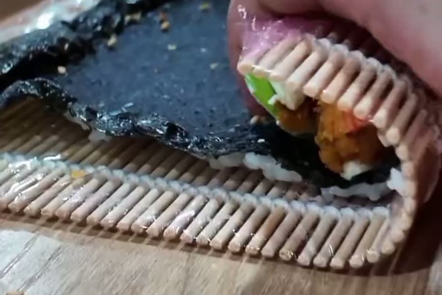 Un maki en cours de roulage sur une natte de bambou